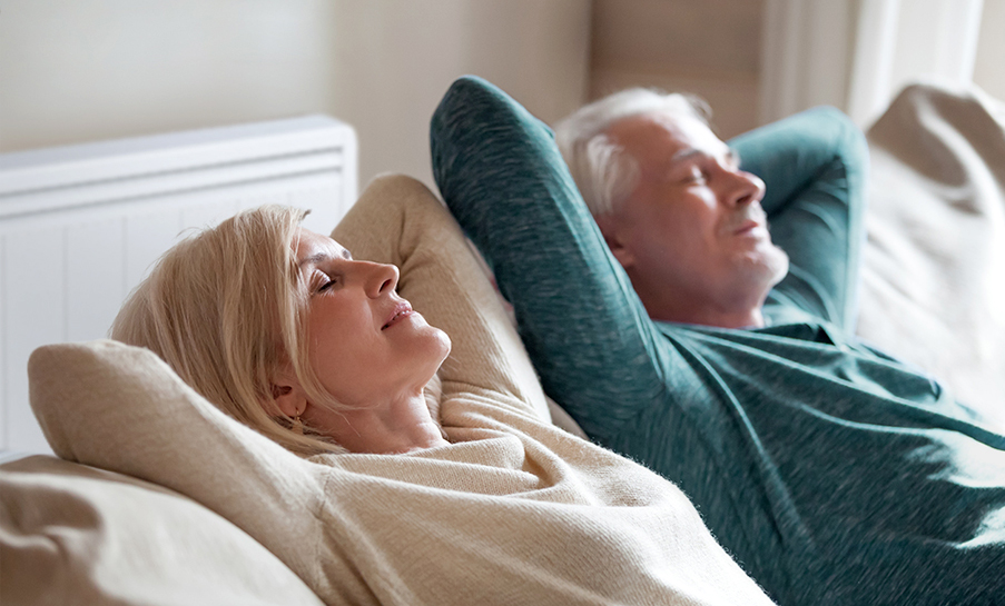 couple detendu sur canape avec radiateur a inertie Aterno en fond