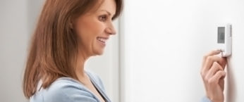 femme qui regle son chauffage avec son thermostat