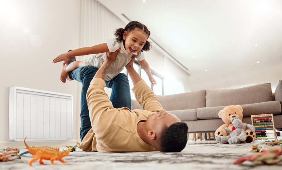 pere avec sa fille jouant au salon - profitant des avantages du chauffage electrique aterno