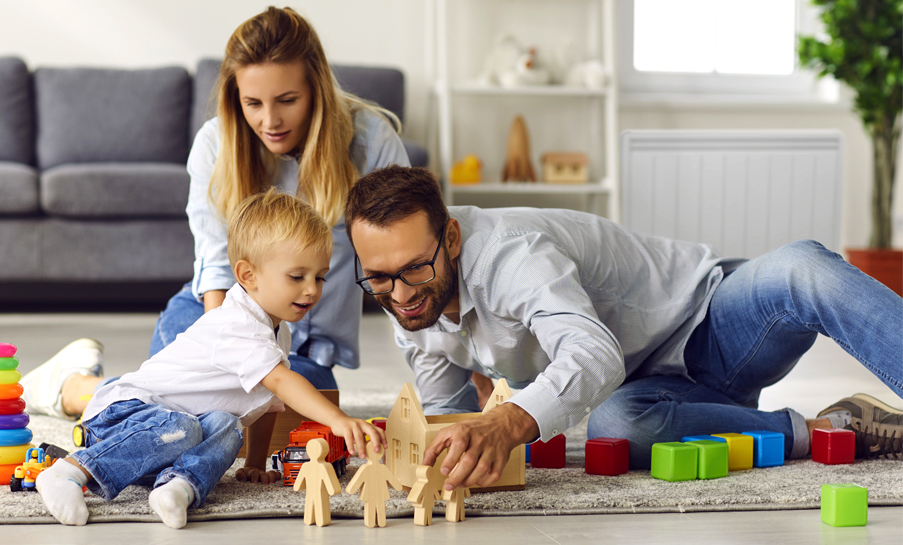 famille dans un salon jouant au sol avec un radiateur a inertie en arriere-plan