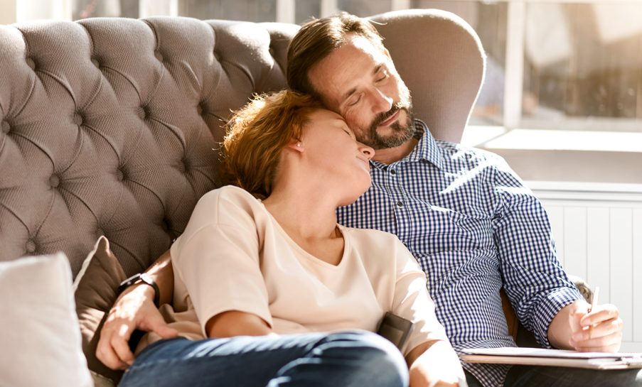 couple confortablement installé sur un canapé, profitant d'un moment de détente procuré par le chauffage à inertie aterno